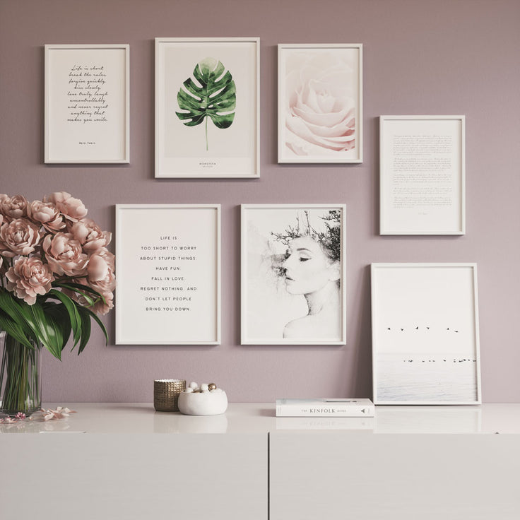Bilderwand auf rosaroter Wand über einem weißen Sideboard