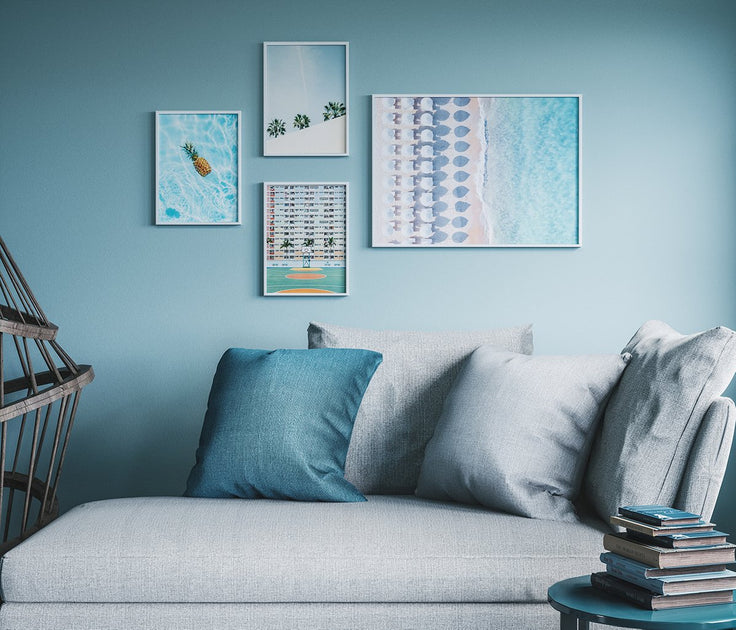 Bilderwand auf blauer Wand über grauem Sofa