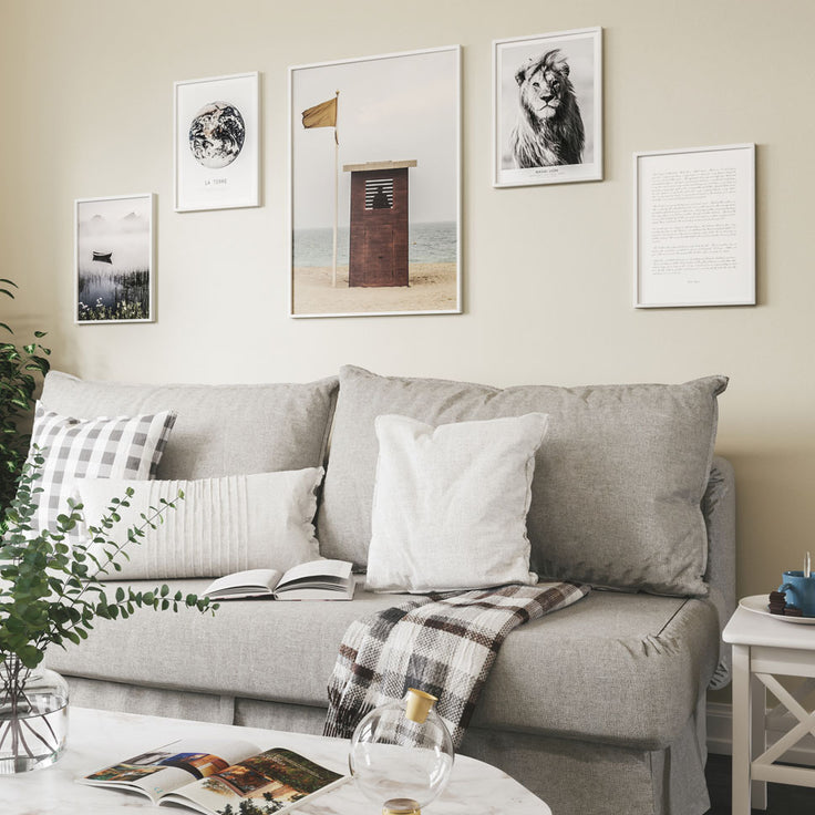 Schöne Bilderwand auf gelber Wand über dem Sofa.