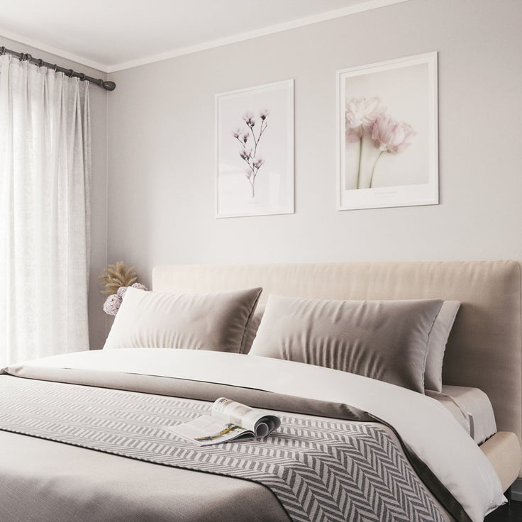 Schöne rosa Blumenbilderwand über stilvollem Bett.